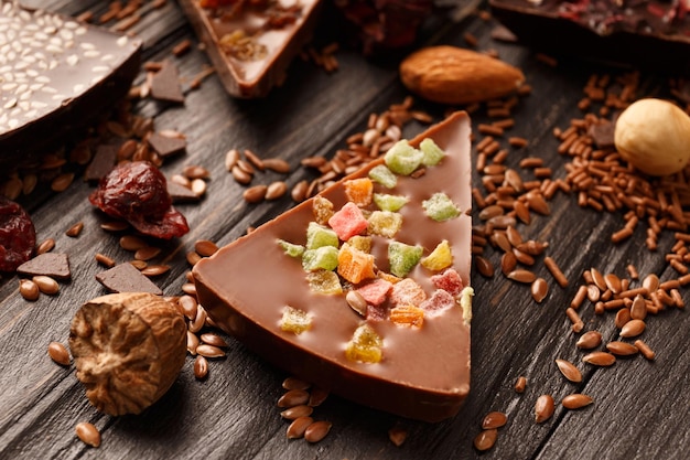 Composición creativa de chocolate en forma de pizza con frutas confitadas, nueces, bayas secas, pizza de chocolate e ingredientes sobre un fondo de madera oscura.