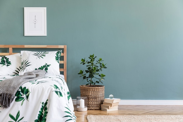 Composición creativa de dormitorio acogedor y elegante con marco cama alfombra cubo de madera como mesa de café y accesorios boho pared de eucalipto y suelo de parquet