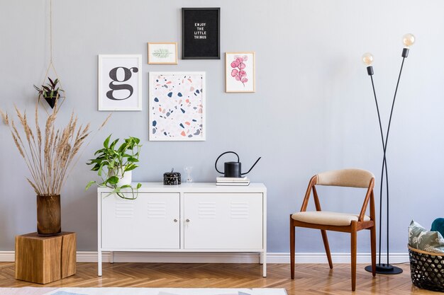 Composición creativa del elegante diseño interior moderno de la sala de estar con marcos de póster, silla con inodoro de madera, almohada, espejo, plantas y accesorios. Suelo de parquet paredes neutras