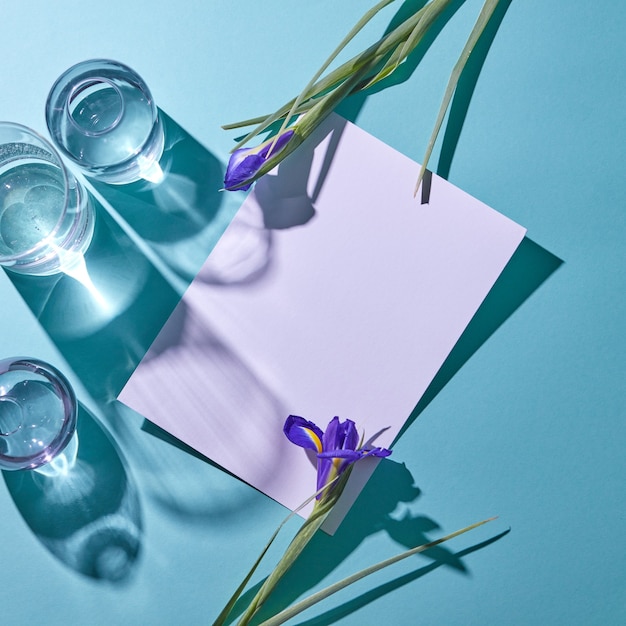 Composición creativa a partir de un conjunto de diferentes jarrones de cristal y flores violetas que decoran un cartón sobre un fondo azul con sombras y espacio de copia, vista superior. Postales para el día de la madre