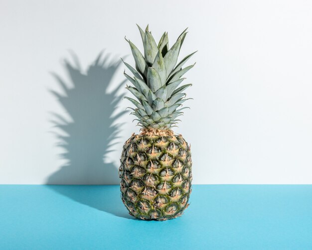 Composición creativa con piña sobre fondo azul.