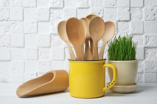 Composición con cucharas de madera en taza sobre mesa contra pared blanca