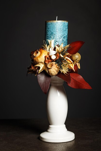 Composición para decoración de interiores con una vela azul y varios elementos florales