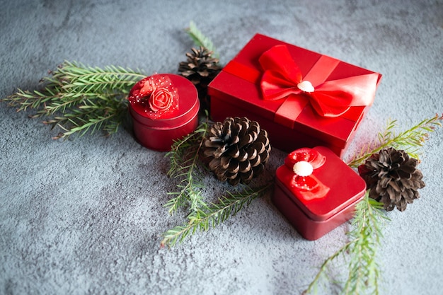 Composición de decoración navideña sobre fondo de hormigón gris con una hermosa caja de regalo roja