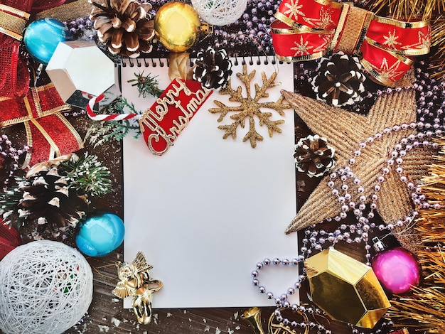 Composición decorativa de Navidad y Año Nuevo. Vista superior, fondo con espacio de copia para su texto. Estrella, conos, cuaderno, juguetes navideños, arcos sobre una mesa de madera con nieve.