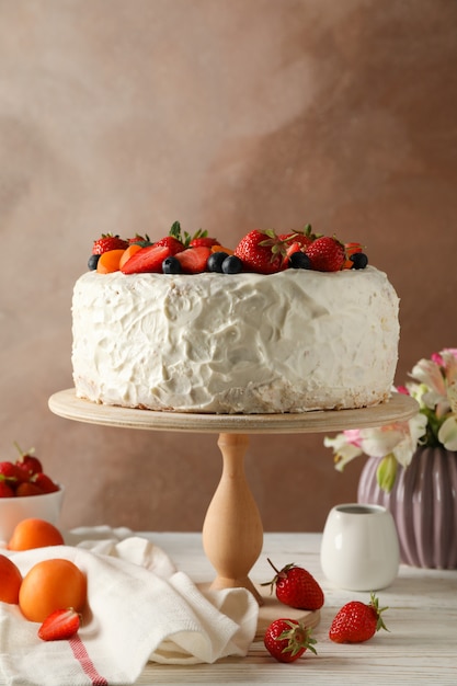 Composición con delicioso pastel de crema de bayas en la mesa de madera blanca. Postre sabroso