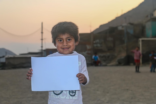 Composición para el Día del Niño. Niño sosteniendo una hoja de papel en blanco para insertar un texto o mensaje