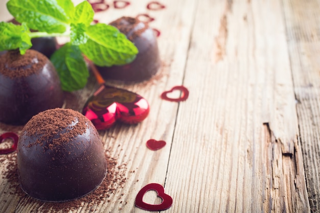 Composición del día de San Valentín con caramelos de chocolate y corazones sobre superficie de madera vintage. Foto tonificada con espacio para copiar texto