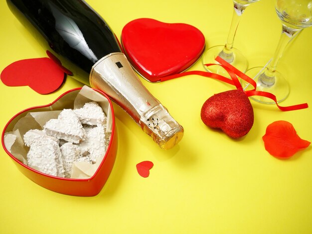Composición del día de San Valentín con champán y dulces en caja en amarillo