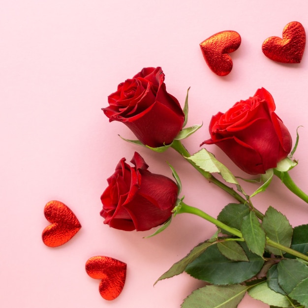 Composición para el día de san valentín. Ramo de rosas rojas y corazones sobre fondo rosa