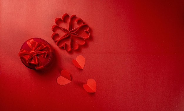 Composición del día de san valentín sobre fondo rojo con corazones de papel rojo y caja de regalo