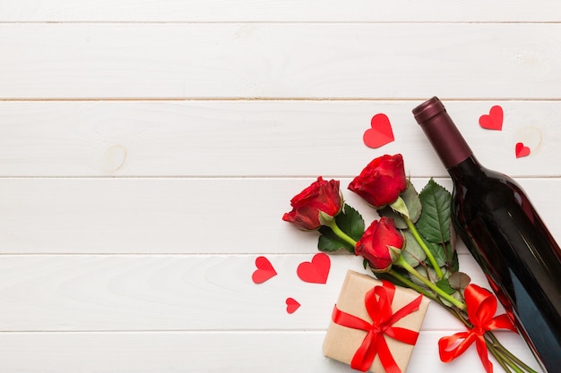Composición para el día de San Valentín con vino rojo, flor de rosa y caja de regalos en la mesa.
