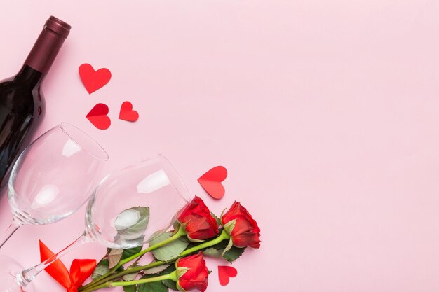 Foto composición para el día de san valentín con vino rojo, flor de rosa y caja de regalos en la mesa.