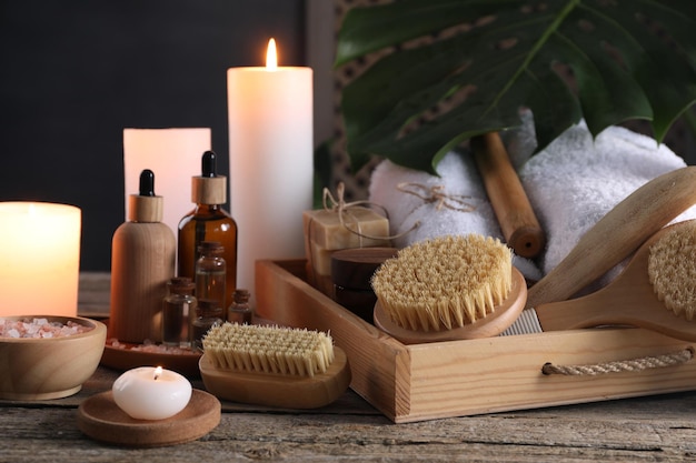 Composición con diferentes productos de spa y velas encendidas en una mesa de madera