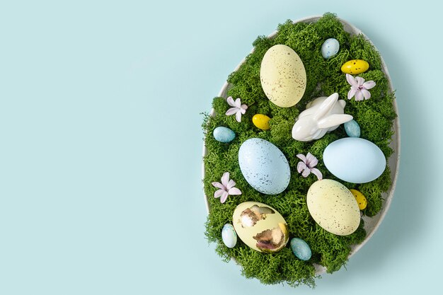 Composición diy de pascua en plato para mesa festiva con huevos de conejo musgo y flores de primavera