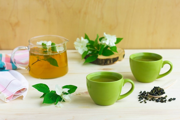 Composición, con dos tazas de té de hierbas verde con flor de jazmín y tetera