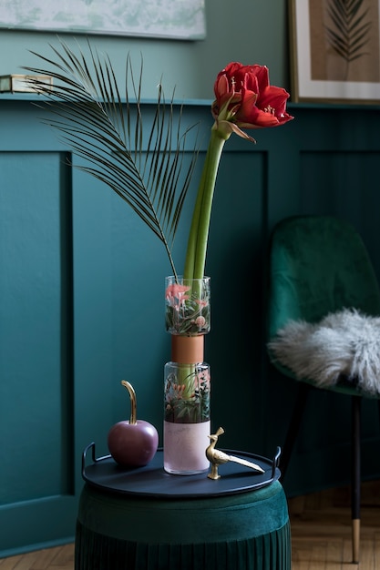 Composición elegante y floral de hermosas flores en jarrón moderno sobre el puf de terciopelo con elegantes accesorios y muebles. Concepto de flor en la sala de estar. Paredes verdes. Diseño de interiores. Plantilla.