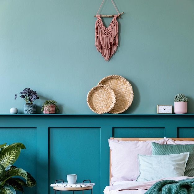 Composición elegante del interior del dormitorio con cama de madera, muebles de diseño, estantería, plantas, decoración y elegantes accesorios personales. Hermosas sábanas, manta y almohada. Plantilla. Puesta en escena en casa.