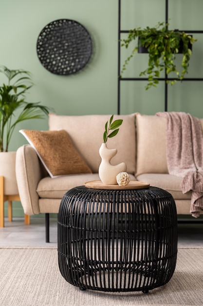 La composición elegante en el interior de la sala de estar con plantas de mesa de centro de sofá beige de diseño y elegantes accesorios personales Almohada marrón y cuadros Acogedor apartamento Decoración del hogar