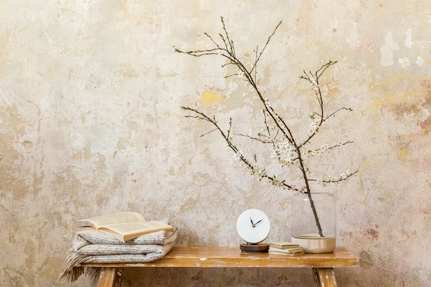 Composición elegante en el interior de la sala de estar con reloj de diseño, banco de madera, flores secas en jarrón, pared grunge y elegantes accesorios personales en la decoración del hogar moderno. Copie el espacio.