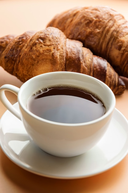 Composición de enfoque selectivo con una taza de té y primeros planos de croissants.