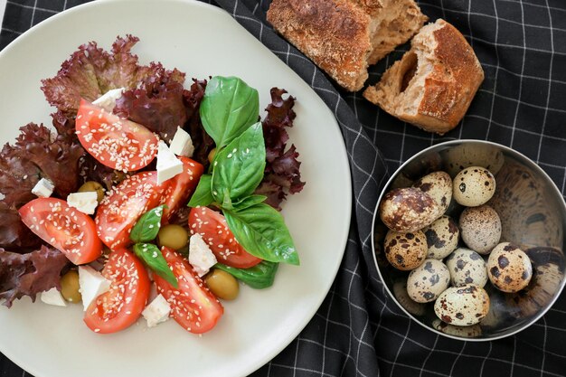 Composición con ensalada de tomate y huevos de codorniz sobre tela escocesa