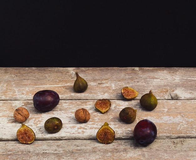 Composición de estilo antiguo hecha de higos, ciruelas y nueces sobre una mesa de madera antigua Fondo oscuro