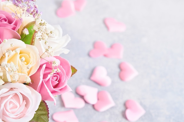 Composición festiva con hermosas flores rosas delicadas en caja redonda rosa con corazones rosas sobre fondo gris claro. Endecha plana, copie el espacio.