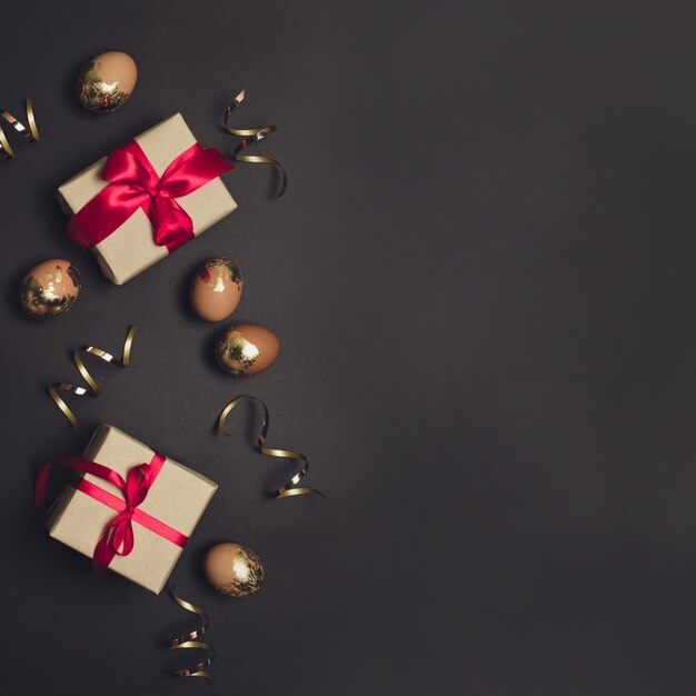 Composición festiva de huevos de oro y cajas de regalo con cinta roja.