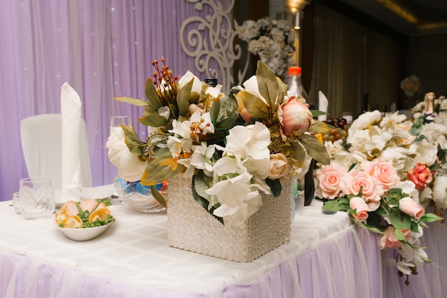 Foto composición de flores artificiales en la mesa de la boda, decoración de la mesa del banquete en un restaurante