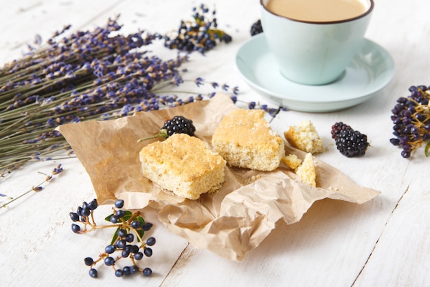 Composición de flores de café, galletas, bayas y lavanda, primer plano en madera blanca.