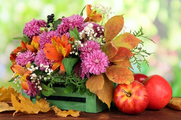 Composición de flores en caja con manzanas en mesa de madera