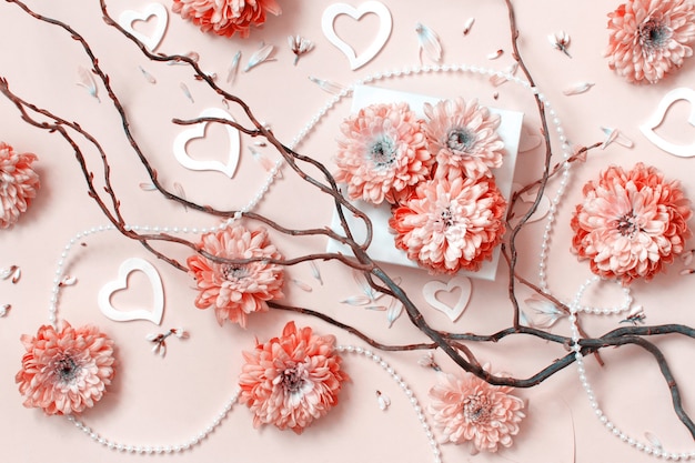 Composición de flores con corazones sobre un fondo rosa pastel