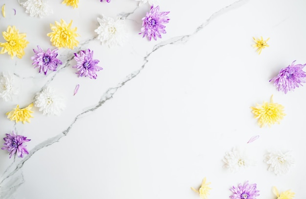 Composición de flores con flores de crisantemo blancas moradas y amarillas sobre fondo de mármol blanco