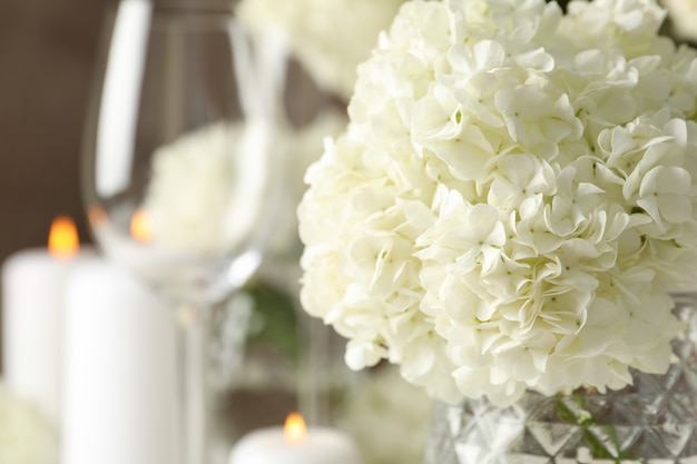 Composición con flores de hortensias y velas contra el espacio marrón. Velada romantica