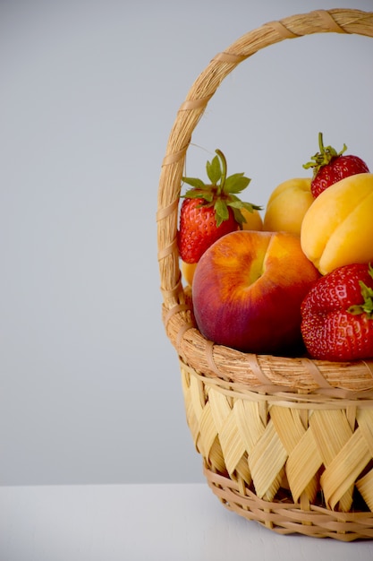 Composición de frutas y bayas frescas en cesta de mimbre cortada a la mitad