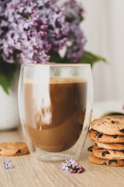 Composición con galletas de chispas de chocolate, cacao y lila en mesa de madera