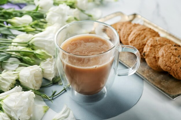 Composición con hermosas flores taza de café y galletas en la mesa