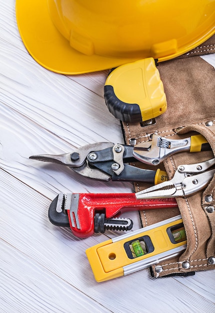 Composición de herramientas de construcción en casco de cinturón de herramientas de cuero en tablero de madera