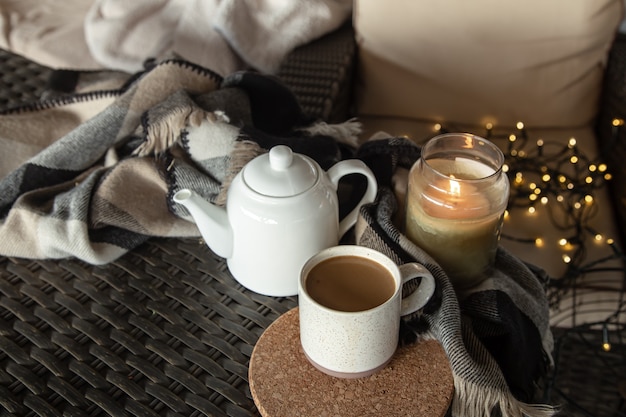 Composición hogareña acogedora con una taza de café, una tetera y una vela encendida. Concepto de confort en el hogar.