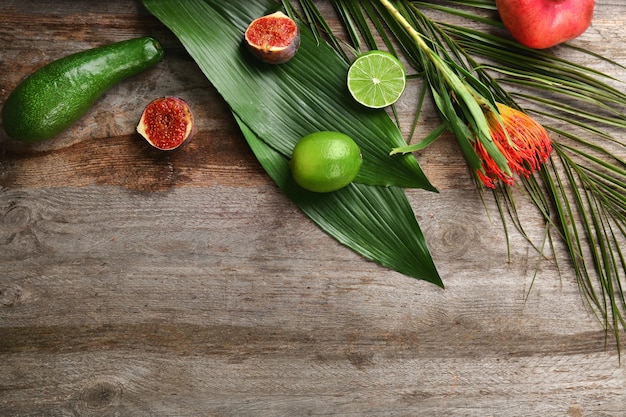 Composición con hojas tropicales y frutas exóticas en la mesa.