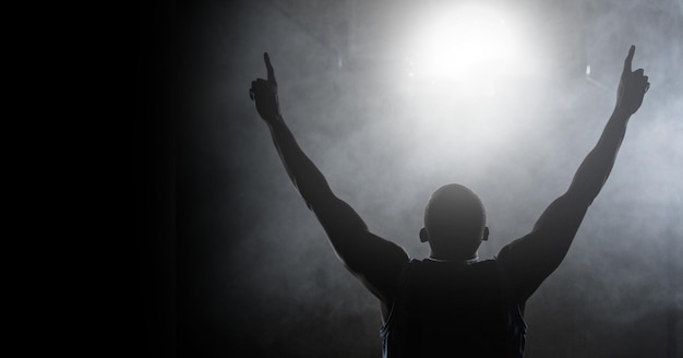 Composición del hombre atlético levantando las manos sobre el desenfoque de blanco y negro