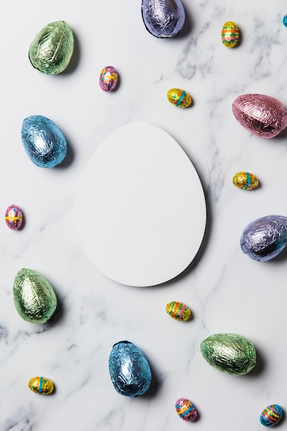 Foto composición de huevos de pascua huevos de pascua de lámina de chocolate alrededor de un cartel en blanco