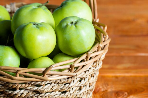 Composición con jugosas manzanas verdes en cesta de mimbre en la mesa Espacio de copia