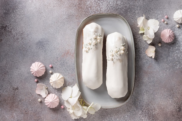 Composición laicos plana con canutillos de chocolate blanco y flores de hortensias, dulces sobre fondo de hormigón rosa. Concepto de comida monocromo