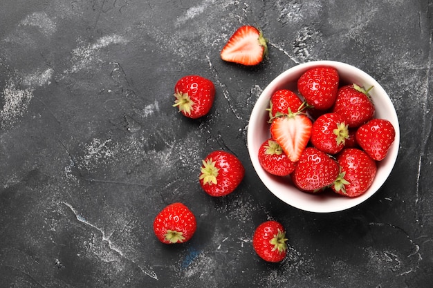 Composición laicos plana con fresas rojas maduras sobre fondo negro