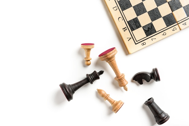 Composición laicos plana con piezas de ajedrez y tablero de ajedrez aislado sobre fondo blanco.