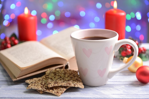 Composición del libro con taza de café y adornos navideños en la mesa sobre fondo brillante