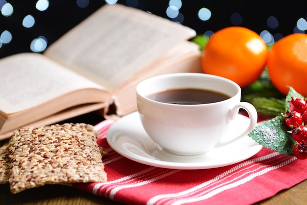 Composición del libro con taza de café y adornos navideños en la mesa sobre fondo oscuro