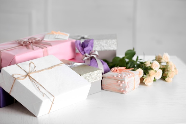 Composición de lindas cajas de regalo y rosas en mesa blanca